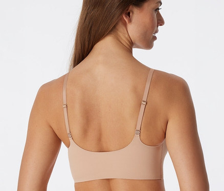 Femme de dos portant une brassière invisible SCHIESSER beige avec coussinets.