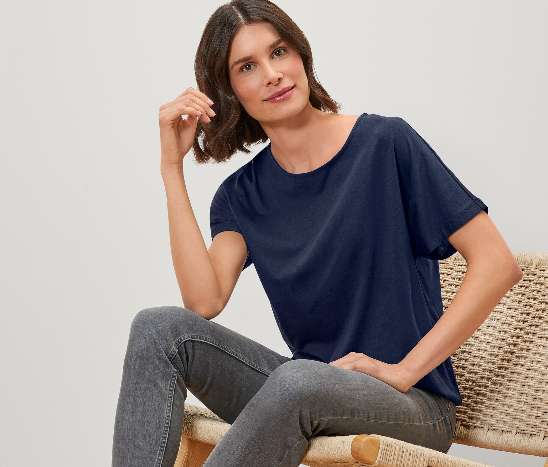 Femme assise sur une chaise portant une blouse bleu foncé.