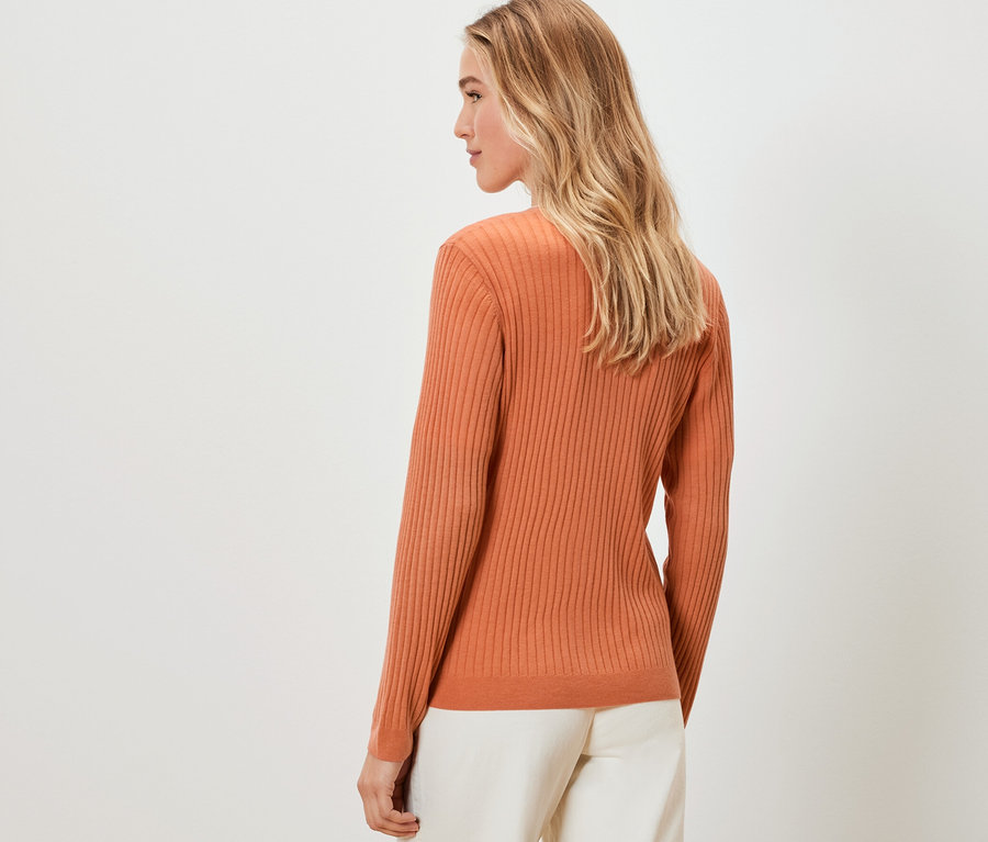 Femme blonde portant un cardigan en soie orange, vue de dos.