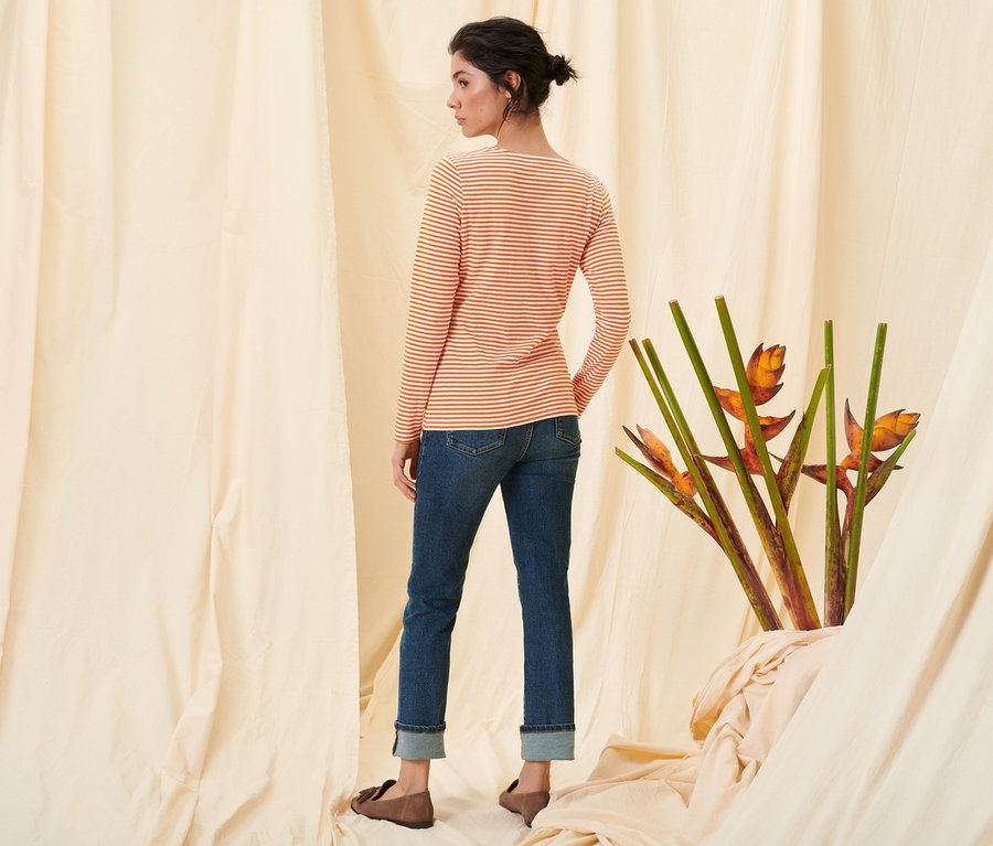 Une femme, vue de dos, porte un t-shirt manches longues à rayures orange, un jean droit en denim « Fit Kira » et des loafers en cuir velours.