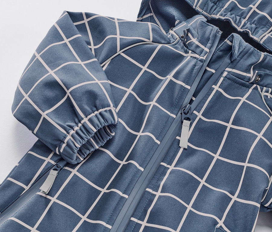 Gros plan sur une combinaison softshell pour enfant à carreaux avec fermeture éclair.