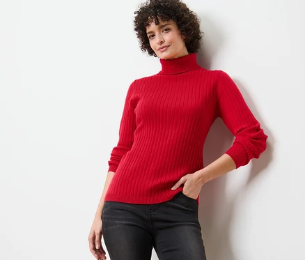 Femme posant dans un pull à col roulé côtelé rouge.