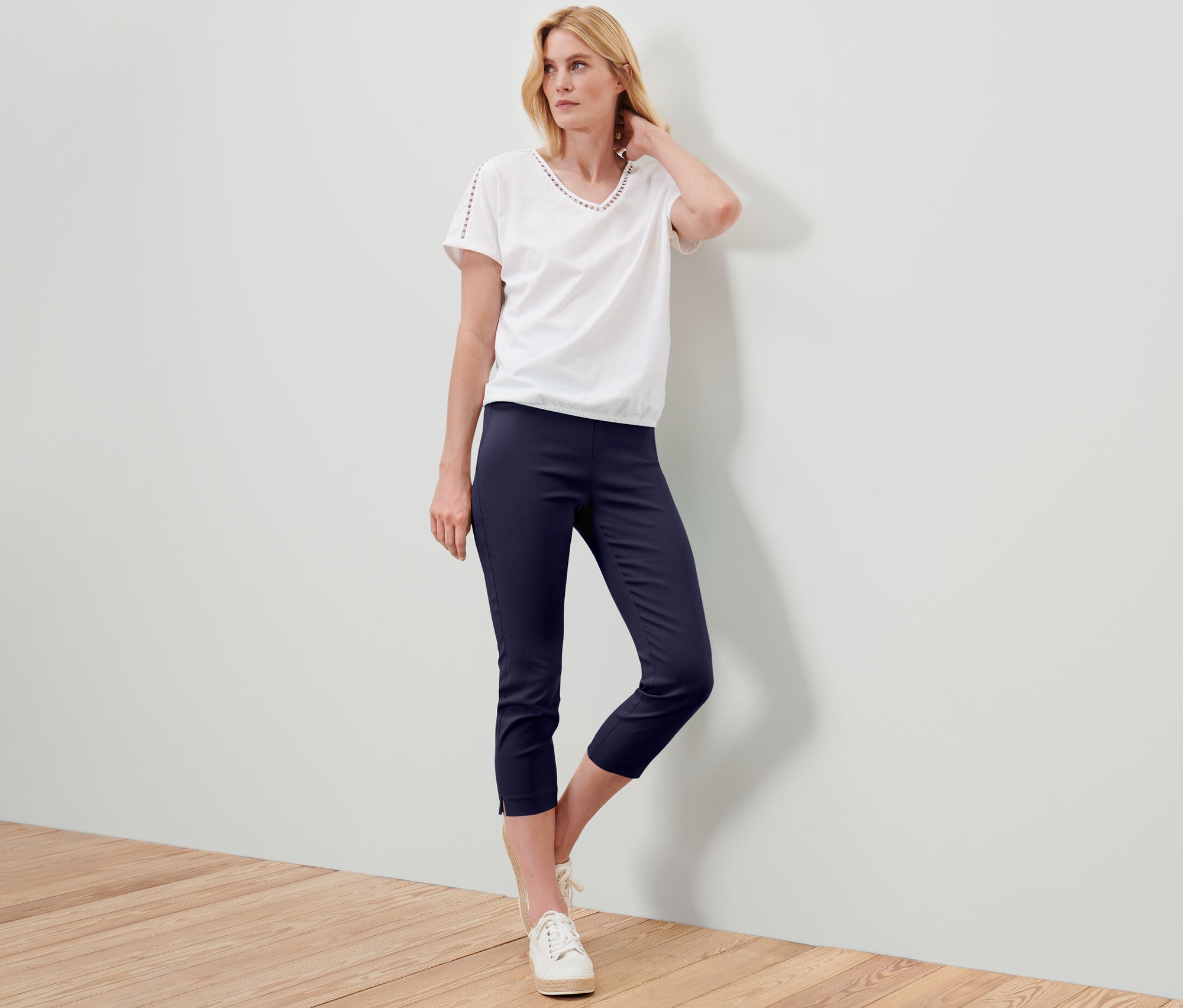 Femme posant en t-shirt blanc et pantalon stretch 7/8 bleu foncé.