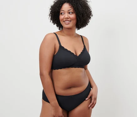 Femme aux cheveux bouclés posant en soutien-gorge souple noir.