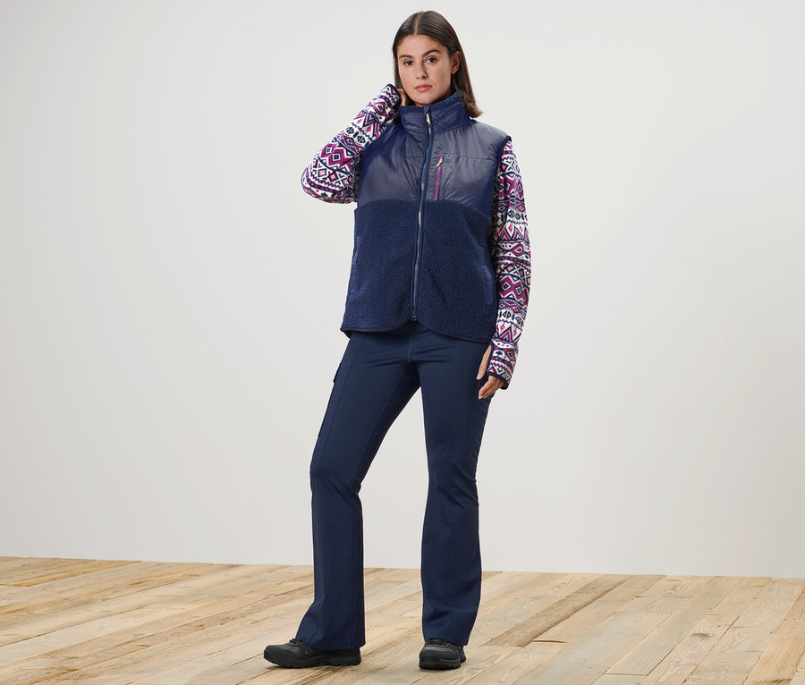 Femme posant en gilet en peluche, pull en polaire et pantalon jazz thermique.
