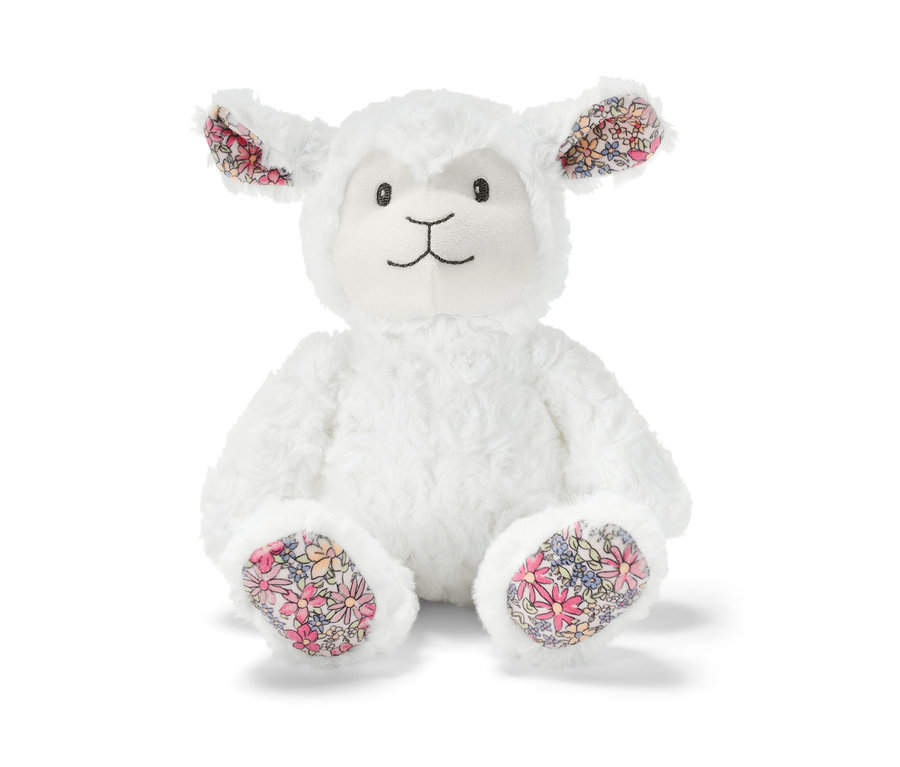 Un mouton en peluche est assis. Les oreilles et les pieds ont un motif floral.