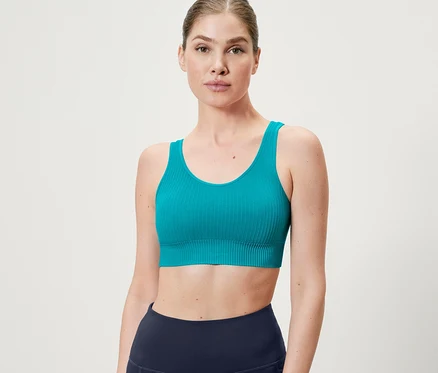 Femme portant une brassière de sport Seamless turquoise.