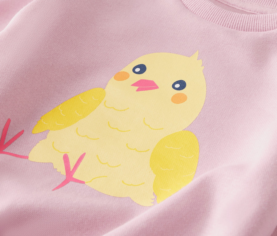 Détail d'un sweat-shirt pour enfant avec un motif de poussin jaune.