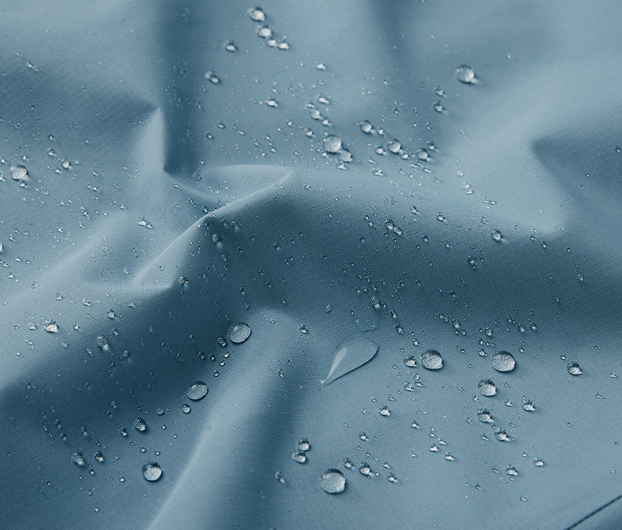 Gros plan sur une veste technique d'extérieur bleue avec des gouttes d'eau.
