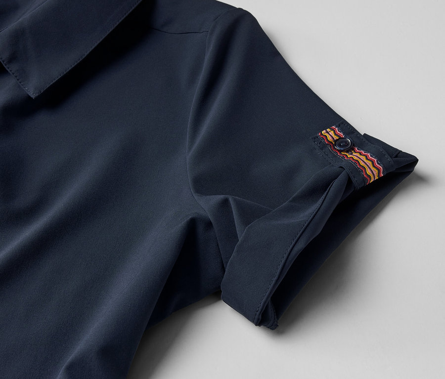 Gros plan sur une robe technique avec un bouton sur la manche.