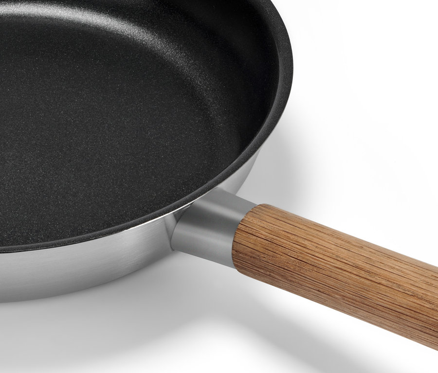 Détail d'une poêle en inox avec manche en bois.