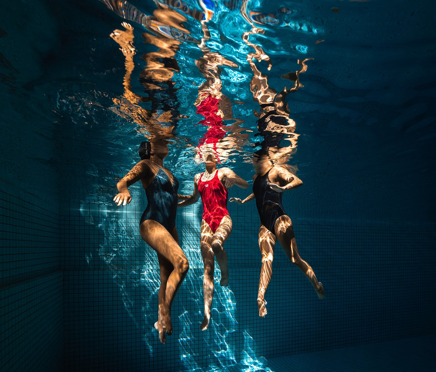 Trois femmes nagent sous l'eau dans une piscine. L'une d'elles porte un maillot de bain sculptant pour femme Lara C-Cup arena.