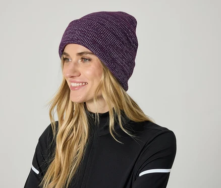 Femme blonde souriant avec un bonnet tricoté violet.
