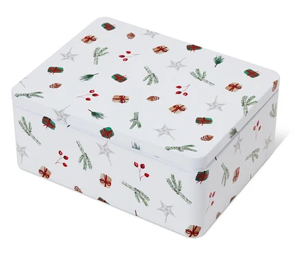 Une boîte en fer blanc blanche avec des motifs de Noël représentant des étoiles, des branches, des baies et des cadeaux.