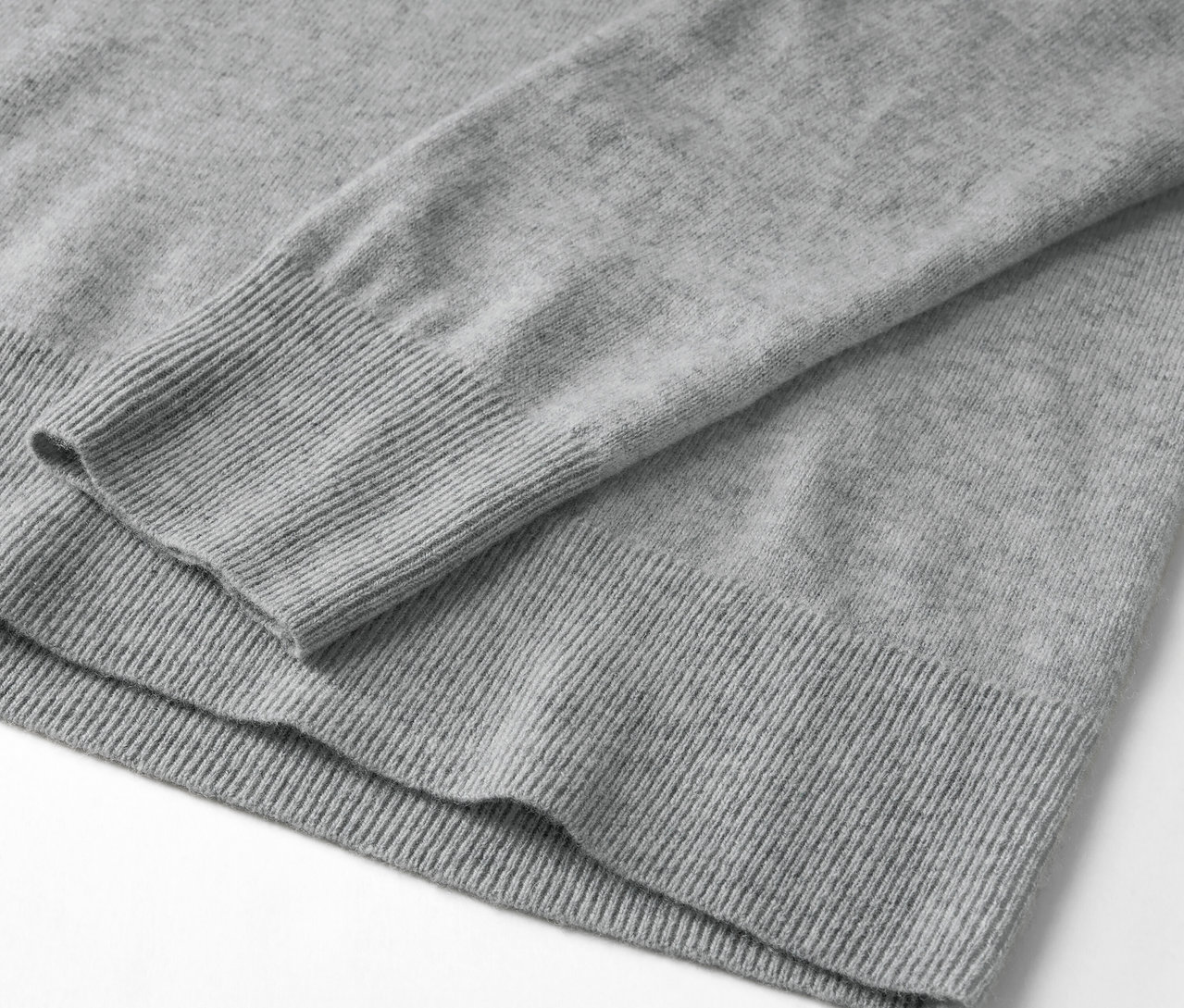 Détail d'un pull gris à manches longues avec ourlet côtelé.