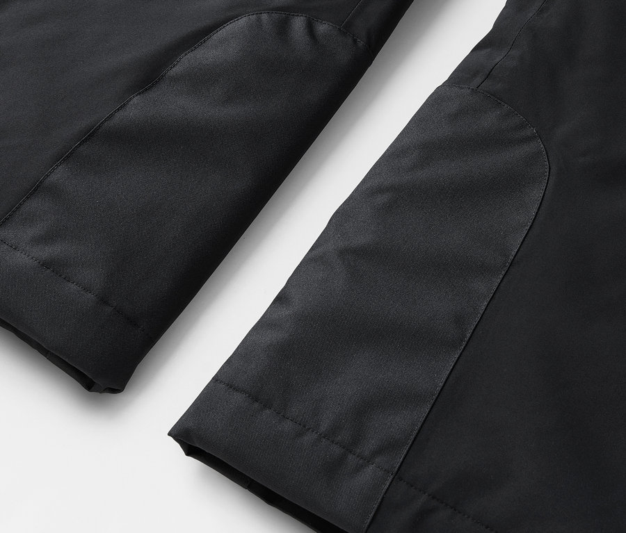 Gros plan sur le bas de jambes d'un pantalon noir avec des empiècements contrastés.