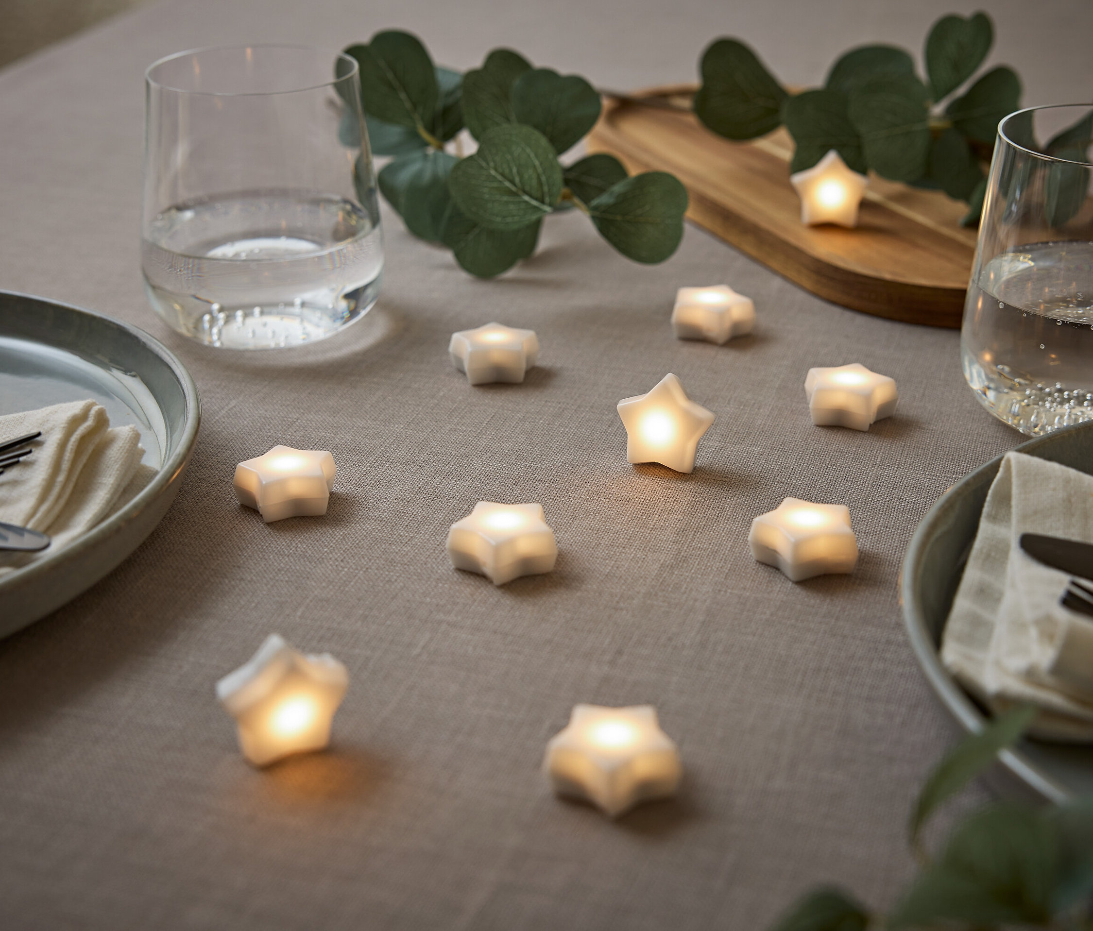 Table dressée avec étoiles, assiettes, verres d'eau et eucalyptus.