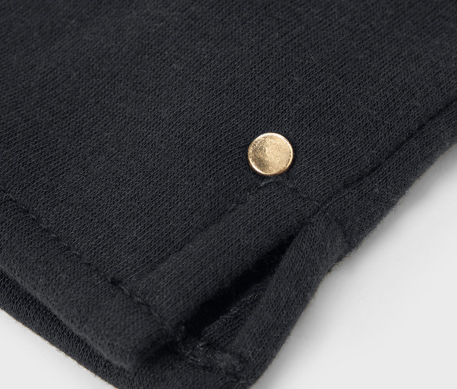 Gros plan sur un tissu noir avec un petit bouton doré.
