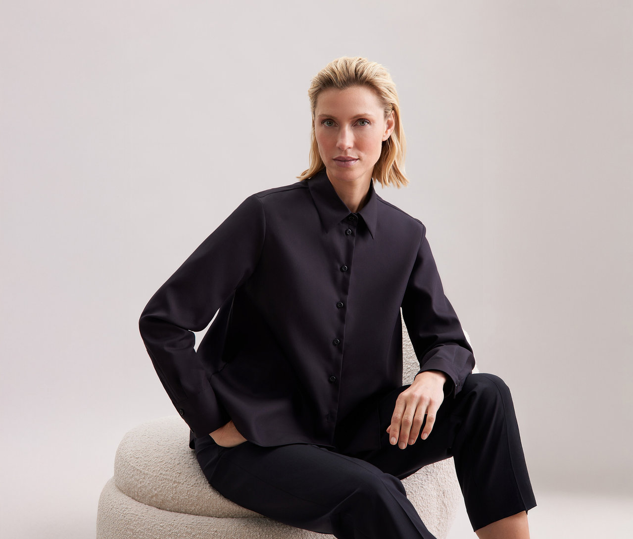 Femme assise portant un chemisier Seidensticker de coupe régulière.