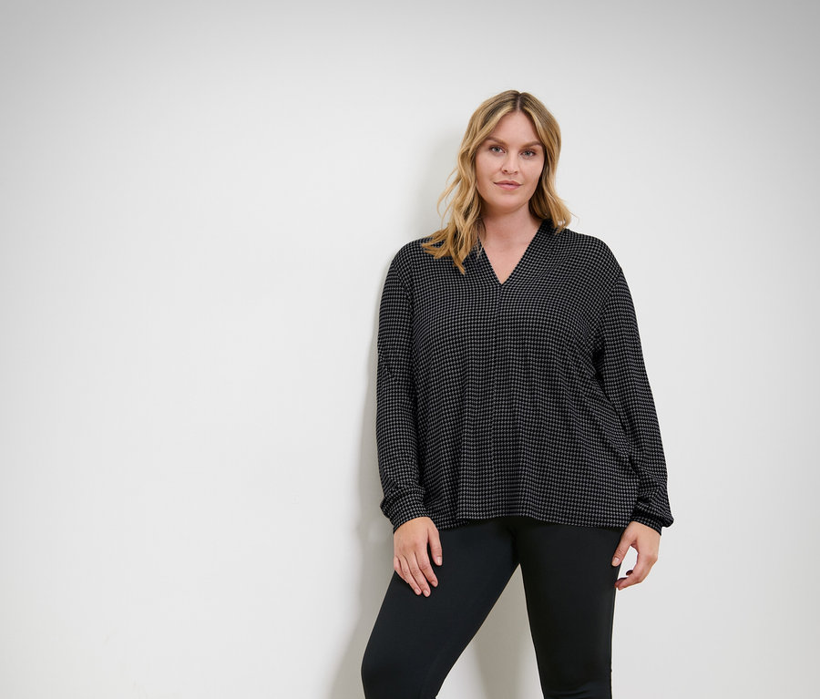 Femme posant dans un haut et un pantalon noirs.