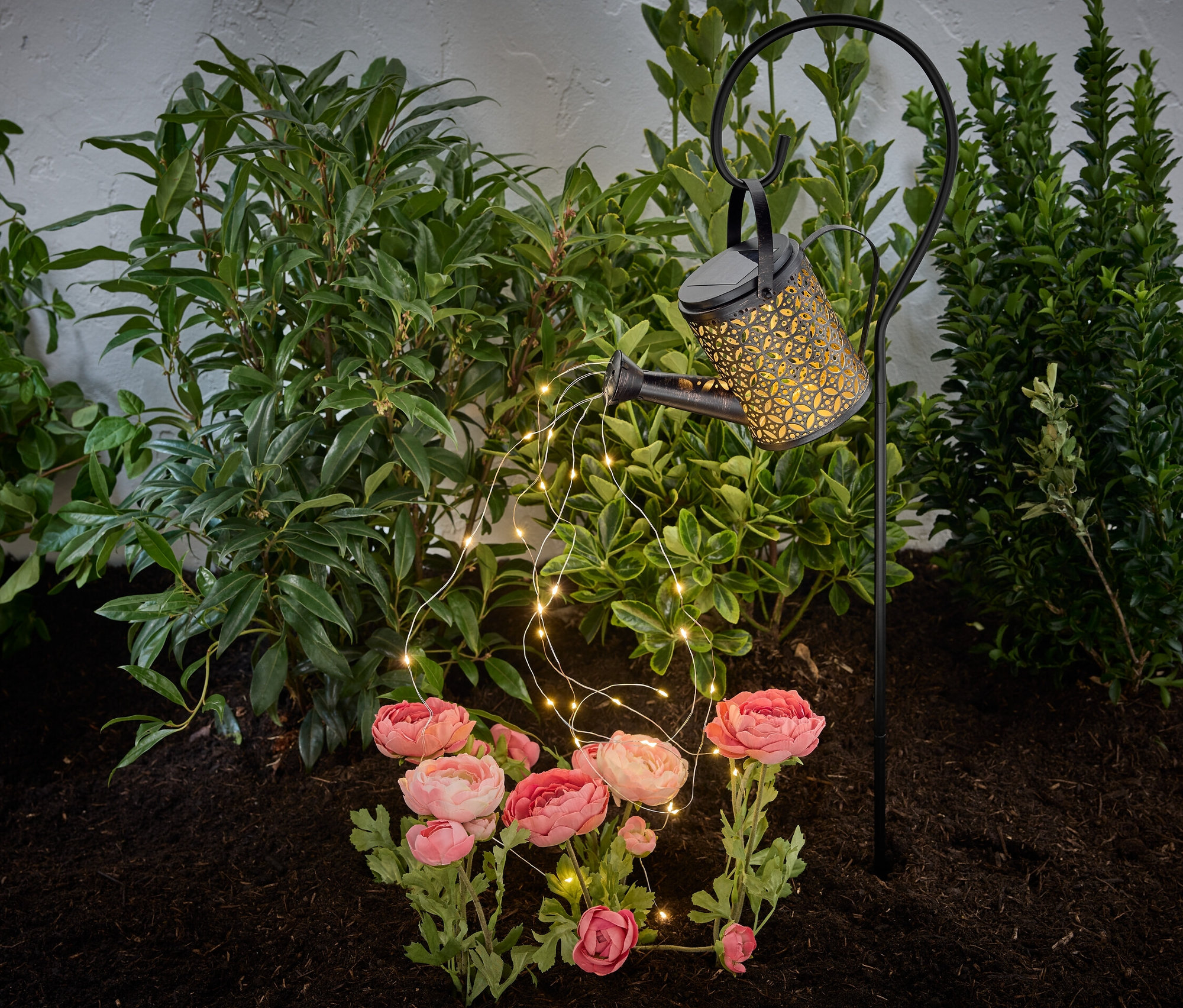 Lampe solaire « Arrosoir » dans un parterre de fleurs.