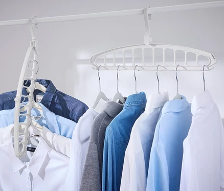 Plusieurs chemises suspendues à une barre blanche avec 2 cintres multifonction.