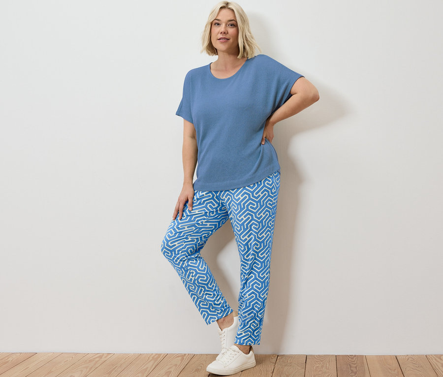 Une femme blonde pose en pantalon en jersey imprimé bleu et t-shirt structuré bleu.
