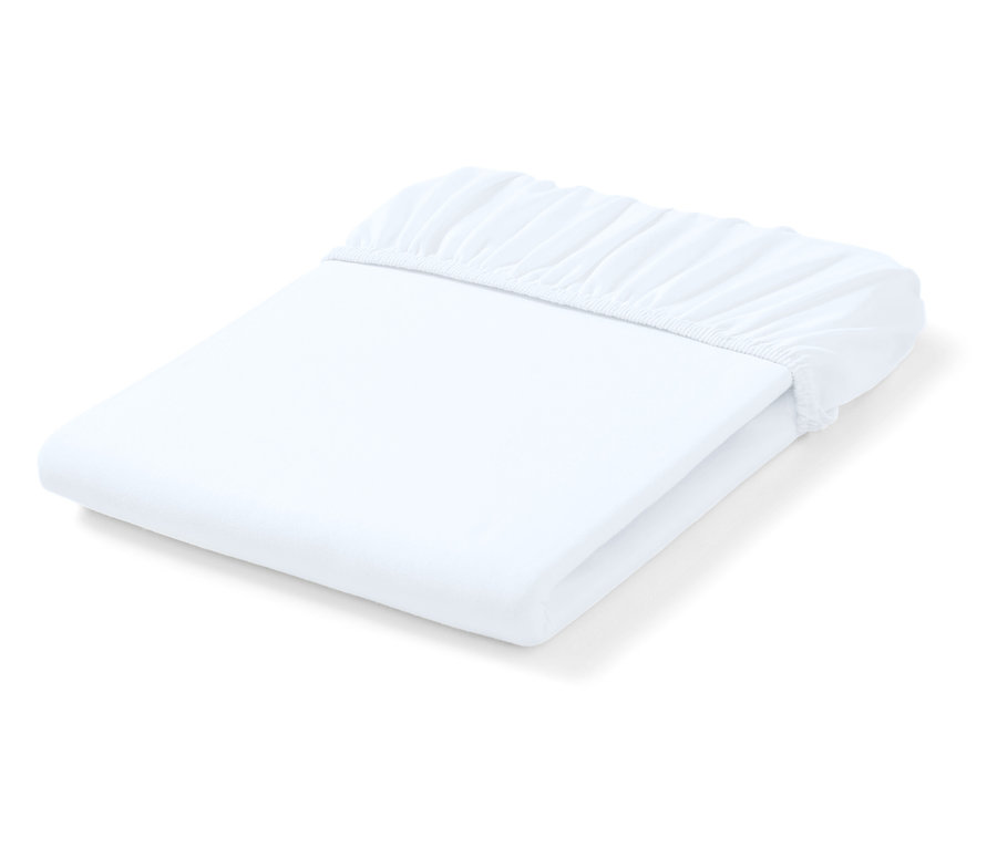 Drap-housse blanc plié avec coins élastiques.