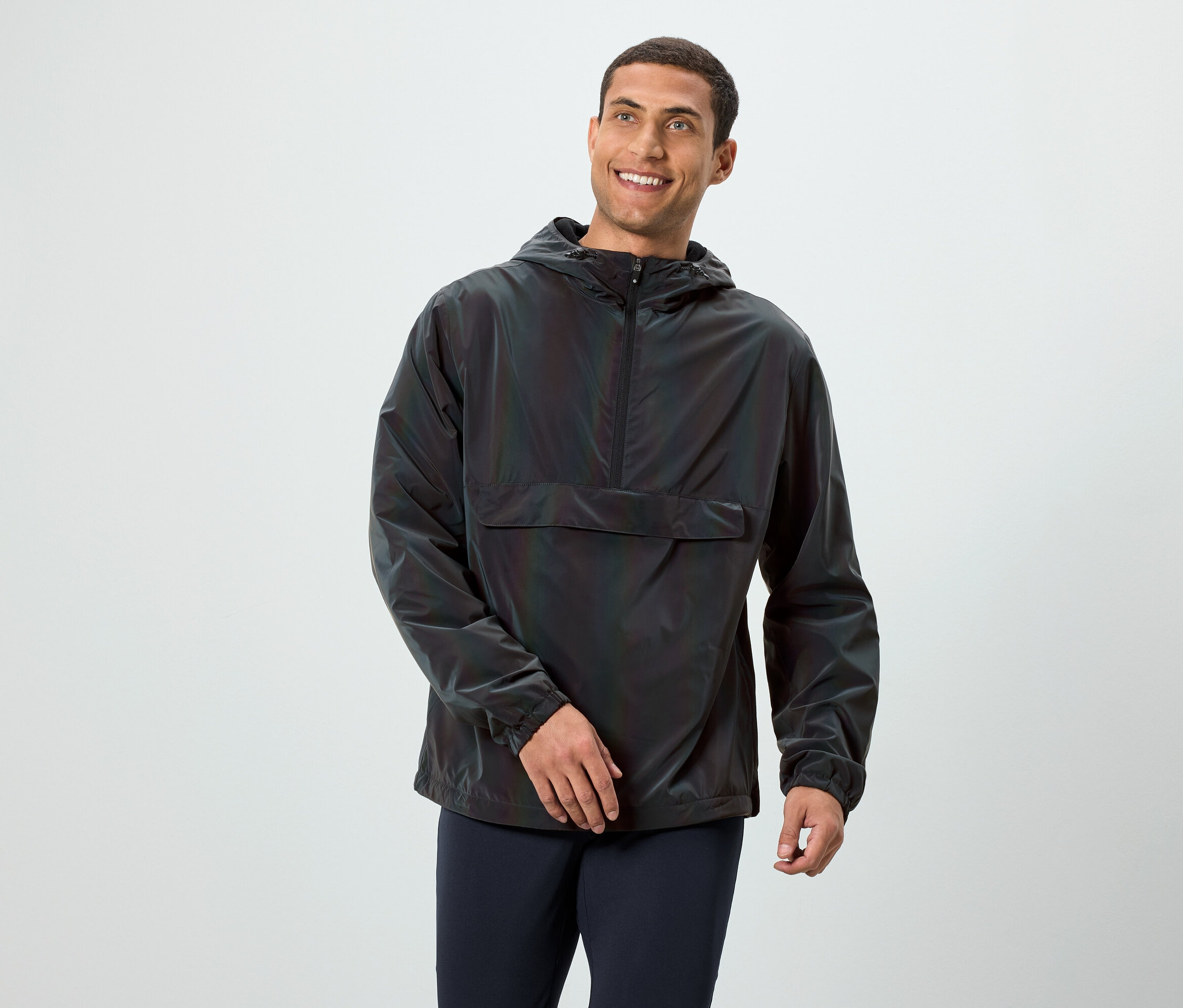 Un homme souriant pose dans une veste à capuche sombre à manches longues.