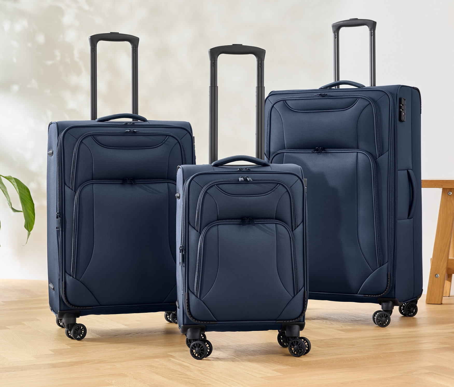 Trois valises en tissu bleues sont posées sur un sol.