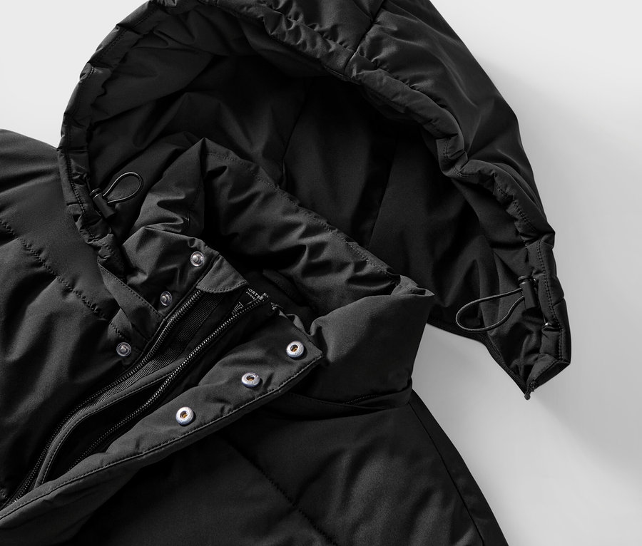 Gros plan d'une veste noire matelassée avec capuche et fermeture éclair.