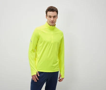 Un homme porte un t-shirt à manches longues jaune néon et un pantalon bleu foncé.