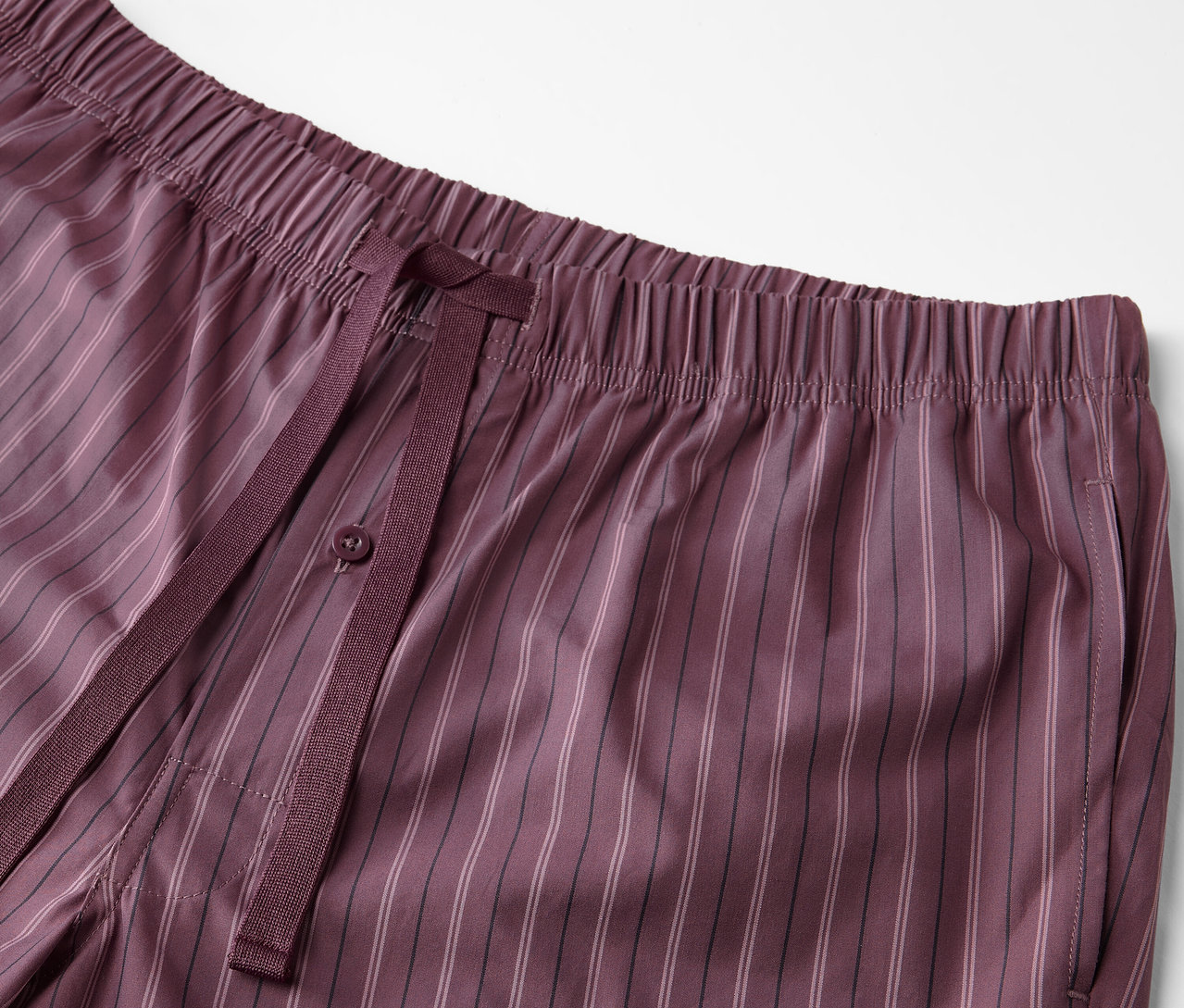 Gros plan sur un pantalon de pyjama bordeaux avec un motif tissé et un cordon de serrage.