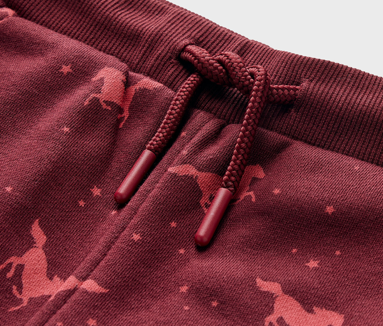 Détail d'un pantalon de jogging pour enfant avec un imprimé de cheval.