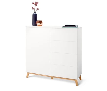 Commode blanche avec quatre tiroirs et des fleurs dans un vase sur le dessus.