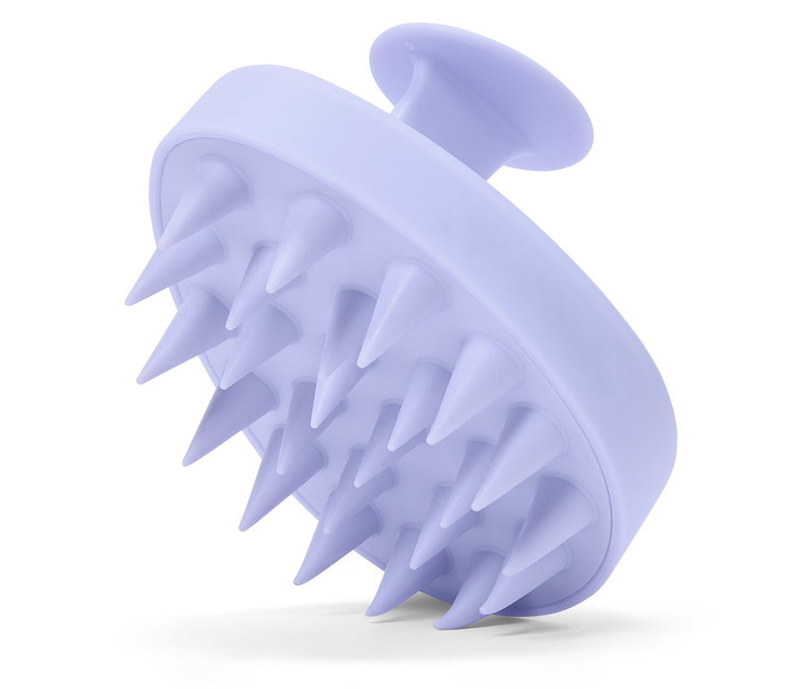 Gros plan d'une brosse de massage du cuir chevelu violette avec des picots.