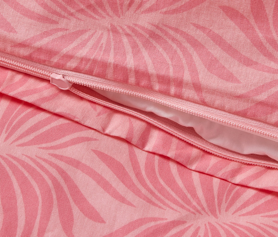 Gros plan d'une parure de lit en percale rose avec un motif de feuilles et une fermeture éclair.