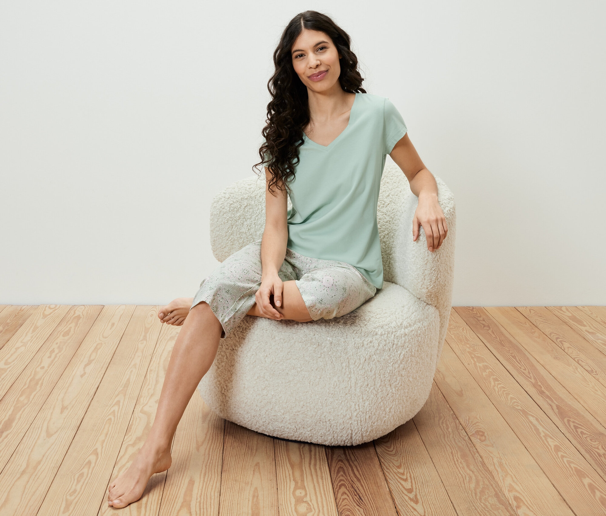 Une femme est assise dans un fauteuil et porte un ensemble pyjama 3/4 vert clair.