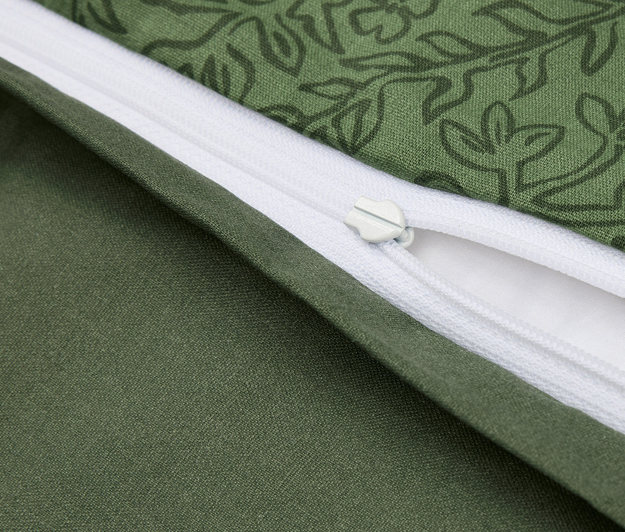 Détail d'une housse de couette verte avec motif floral et fermeture éclair blanche.