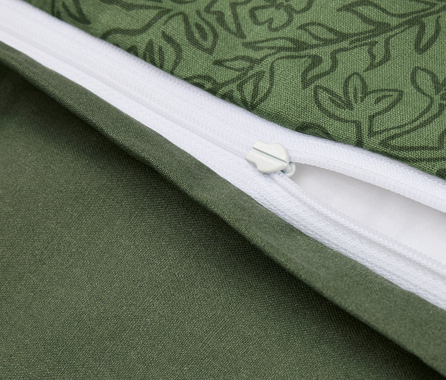 Détail d'une housse de couette verte avec motif floral et fermeture éclair blanche.