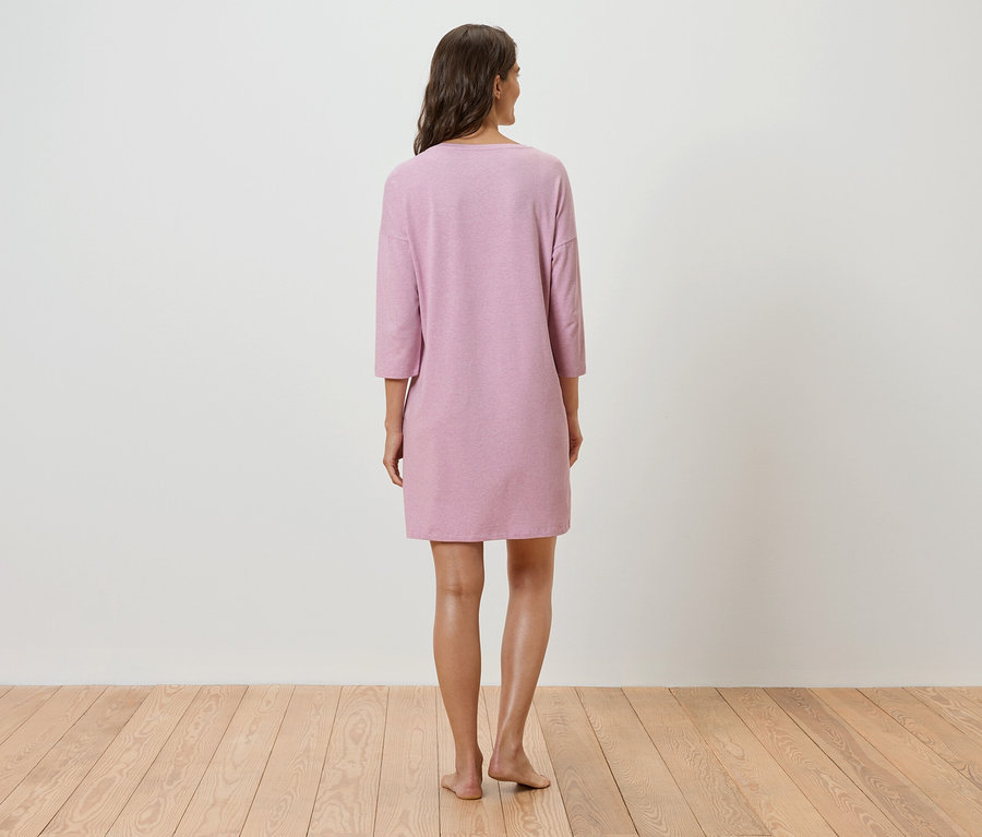 Une femme, vue de dos, porte une robe rose à manches trois-quarts.