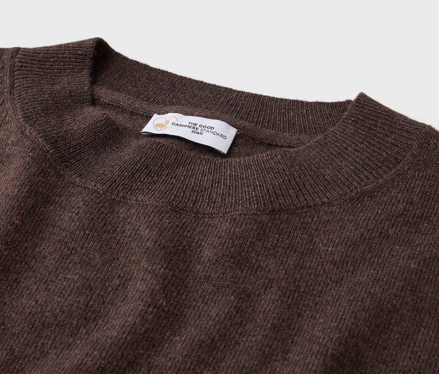 Gros plan d'un pull marron à col rond avec une étiquette.