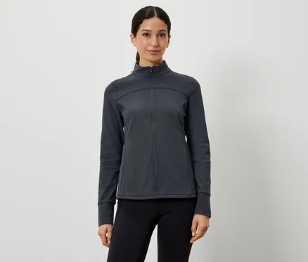 Une femme porte une veste de sport gris foncé et un legging noir.