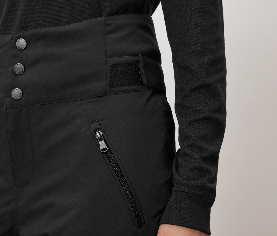 Pantalon noir taille haute avec trois boutons et une poche zippée.