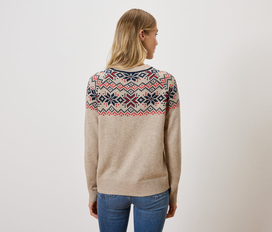 Une femme, dos à la caméra, porte un pull beige à motifs et un jean.