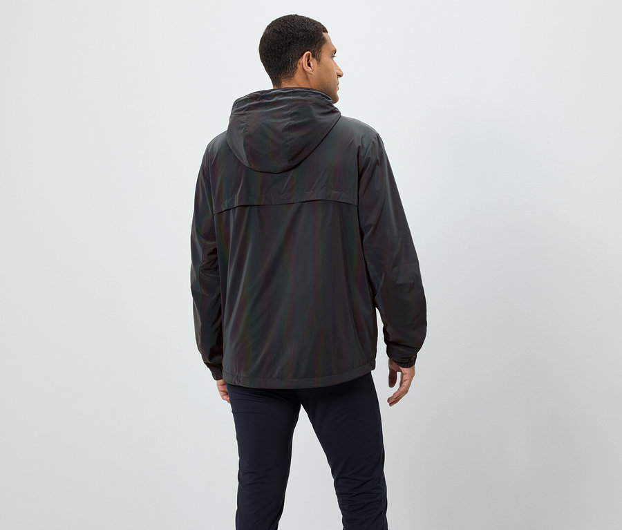 Homme de dos portant une veste irisée à capuche et un pantalon bleu marine.