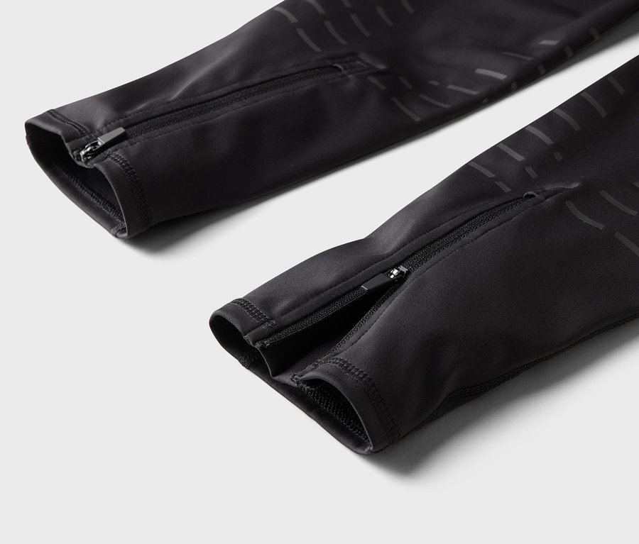 Détail d'un pantalon noir avec fermetures éclair aux chevilles.