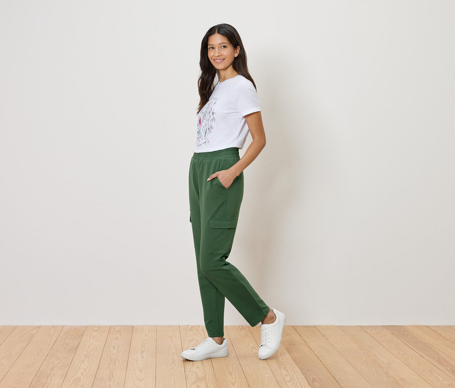Femme portant un t-shirt blanc à motif floral et un pantalon cargo vert.