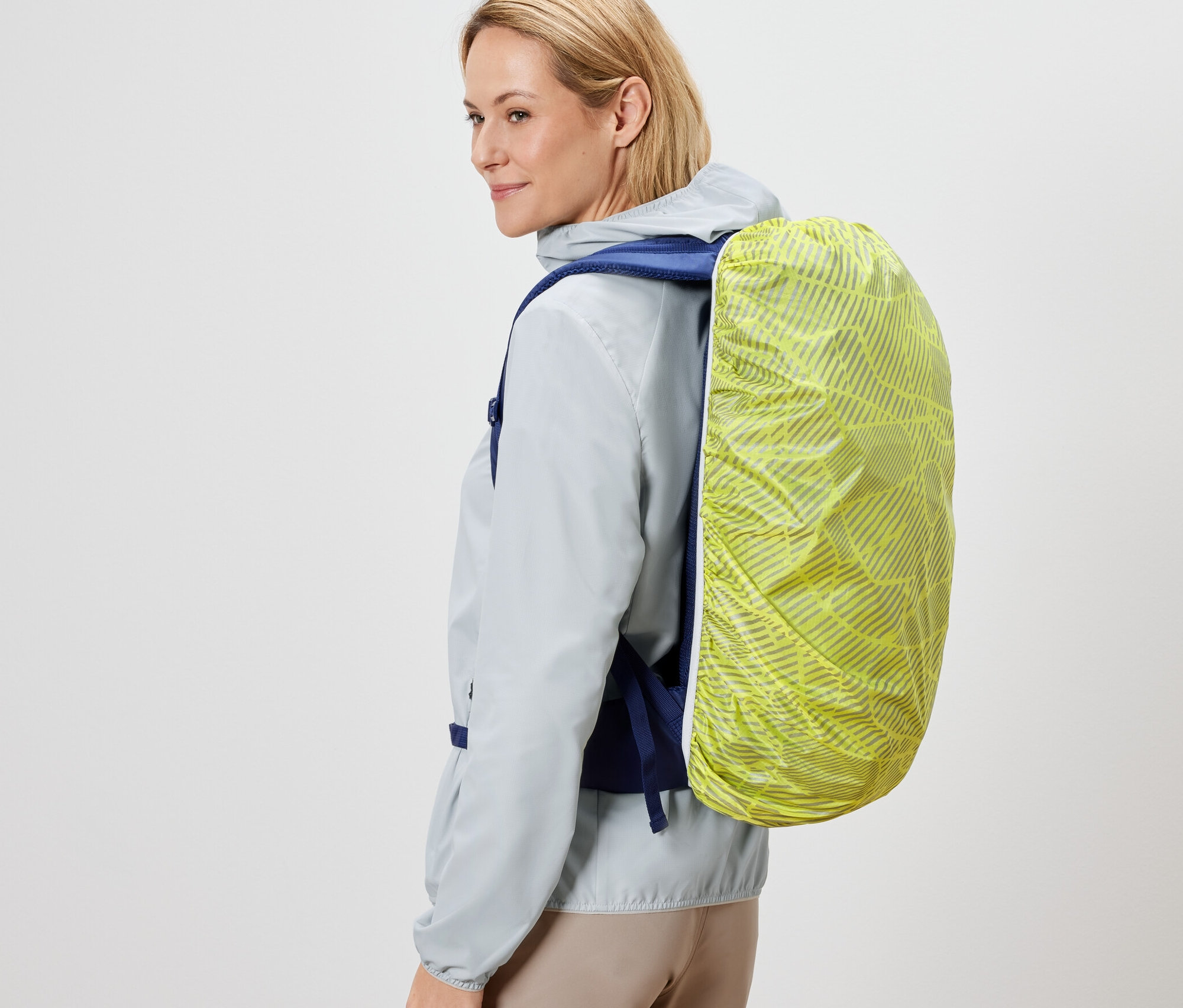 Une femme porte un sac à dos avec une housse de protection pour sac à dos.