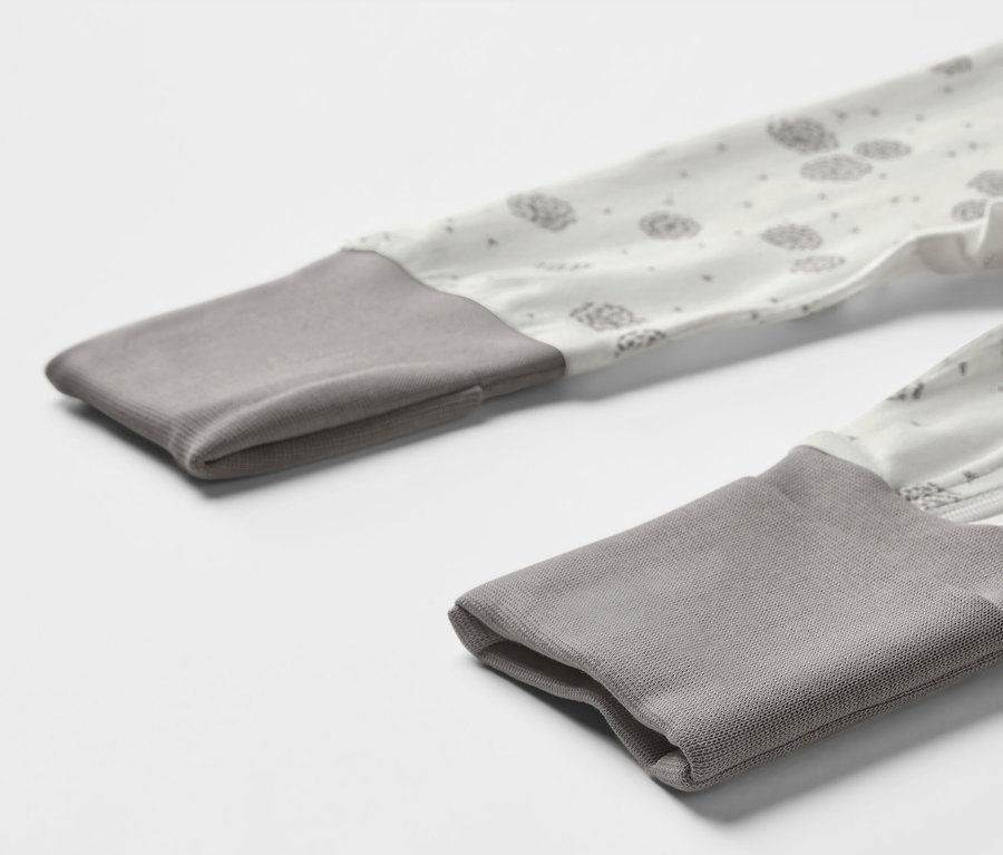 Gros plan sur un des 3 pyjamas pour bébé avec des bords gris et un imprimé de pissenlits.